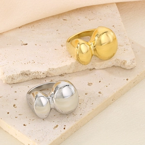 Anelli geometrici in acciaio inossidabile oro e argento su pietra arenaria beige