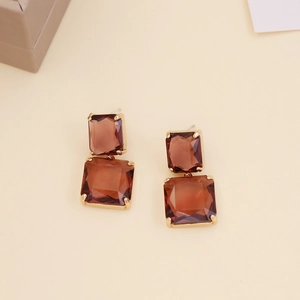 Macro detail of amber crystal drop earrings with golden square stone claw setting