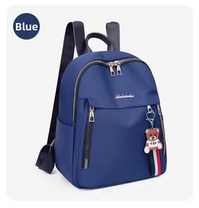 Detail of blue nylon backpack with gold zippers and a cute toy bear keychain accessory