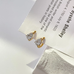 Close-up of gold pear cut cubic zirconia drop earrings on a minimalist stone base