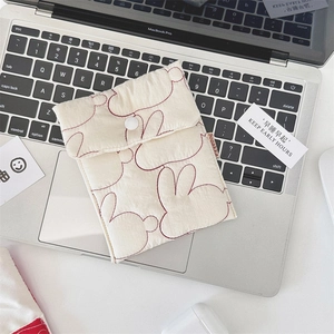 Close-up of beige quilted sanitary bag with red rabbit pattern on a laptop keyboard