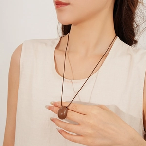 Gros plan d'un long collier de style ethnique avec pendentif en pierre brune sur cordon ciré