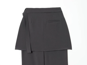 Detail of dark grey suit trousers with unique layered skirt design and matching waist belt