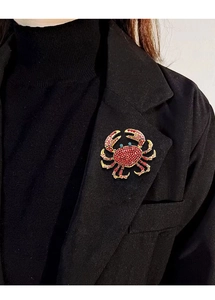 Close-up of a luxury red crystal crab brooch pinned on a black blazer lapel