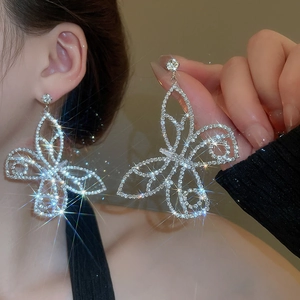 Macro shot of silver butterfly drop earrings with sparkling crystals on female model