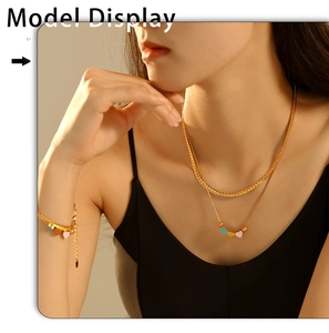 Close-up of a double-layered golden necklace and bracelet set with colorful heart charms