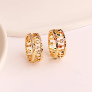Gold hollow geometric ring with colorful and white zircon accents on beige background