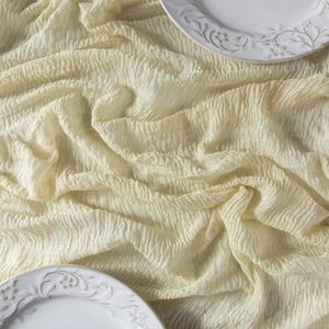 Close-up of beige cheesecloth table runner texture with pleated fabric and ceramic plates
