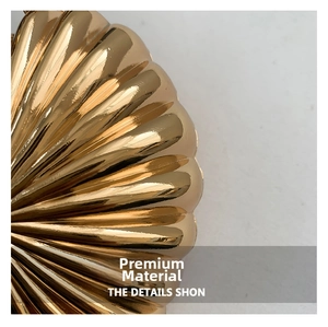Detailed close-up of the heart-shaped gold metallic handbag featuring radiant pleated texture