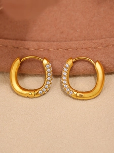 Macro view of gold U-shaped earrings with micro-paved white zircons on wool background