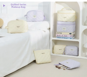 Lifestyle view showing variety of quilted pastel cosmetic bags in a white bedroom setting