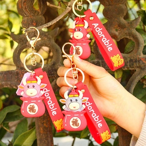 Close-up of cute zodiac ox PVC keychains with silicone straps on a vintage fence