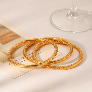 Detailed view of three gold twisted texture stainless steel bangles on a white card