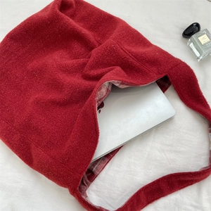 Macro detail of large red felt tote bag showing spacious interior for a laptop