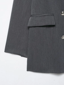 Détail du blazer gris foncé avec boutons métalliques et poche à rabat sur tissu lisse
