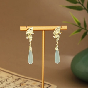 Detail of gold fan earrings with light green teardrop pendants and white rhinestones
