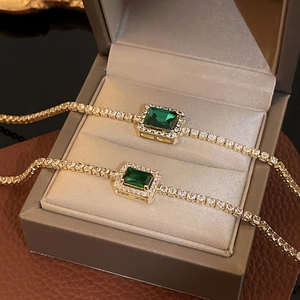 Macro view of emerald-cut green gemstone tennis bracelet with white zircon pavé setting