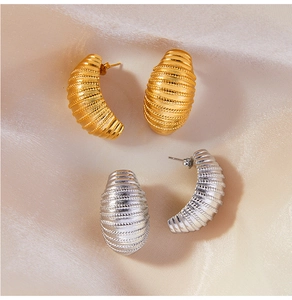 Macro shot of gold and silver C-shaped earrings with textured spiral line patterns