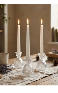 Detailed view of three-piece vintage ribbed glass candlesticks with lit white taper candles
