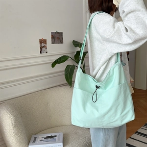 Dettaglio della grande borsa a tracolla verde acqua con coulisse nera e tasca laterale