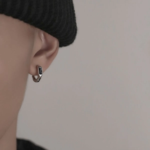 Close-up of minimalist silver hoop earring with rectangular black stone on male model