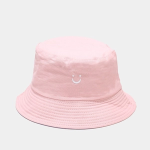 Detail of a pink cotton bucket hat featuring white smiley face embroidery and stitching