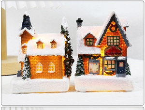 Detail of light-up Christmas candy shop and resin house with warm LED glow and snow