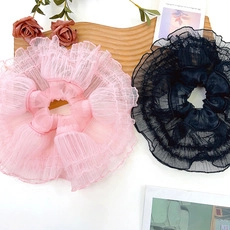 Detailed view of layered mesh scrunchies in pink and black colors on a white surface