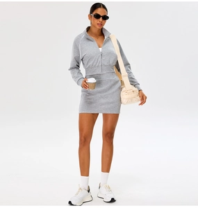 Detail of grey zip-up jacket and matching skirt on a model in a studio setting