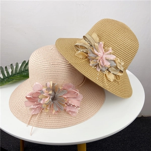 Close-up of woven sun hats featuring handmade chiffon flowers and white pearl accents
