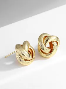 Detailed close-up of golden twisted knot earrings featuring fine brushed metal textures