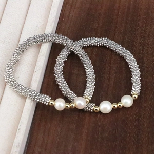 Detail view of two-piece handmade beaded bracelet with white pearls and gold accents