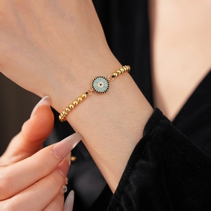 Gros plan du bracelet perlé œil bleu en or avec zircon sur le poignet du mannequin