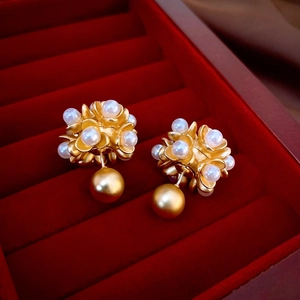 Nahaufnahme der Vintage Goldblumen-Ohrringe mit weißen Perlen auf rotem Samt-Schmuckkästchen