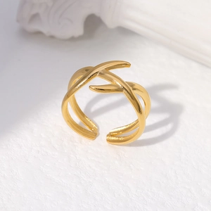 Macro detail of golden irregular cross-wrap stainless steel ring on plaster pedestal