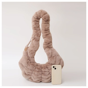 Detail van pluche croissant schoudertas met gewatteerde details en smartphone ter referentie