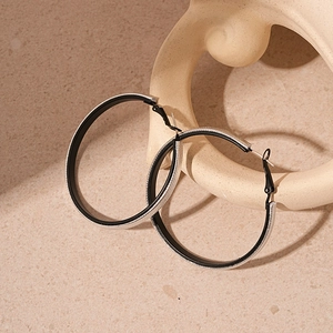 Detail of round faux leather earrings with silver glitter texture and matte black interior
