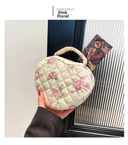Detail of heart quilted cotton makeup bag featuring pink floral print and fabric handle