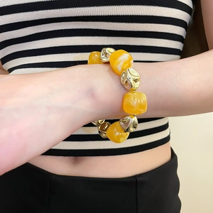 Detail of chunky irregular yellow acrylic beads and gold metallic spheres on a fashion bracelet