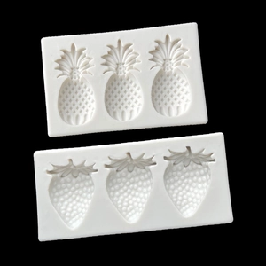 Detailed view of white silicone molds for creating pineapple and strawberry shapes