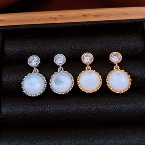 Macro detail of round resin pendant earrings with shell pearls and zirconia in jewelry box