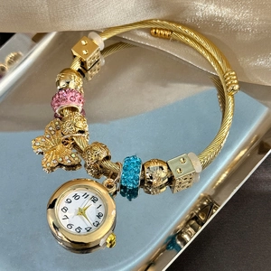 Detail of golden charm bracelet watch featuring butterfly pendant and rhinestone beads