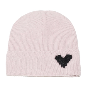 Detail of light pink knitted beanie featuring ribbed texture and black heart patch accent