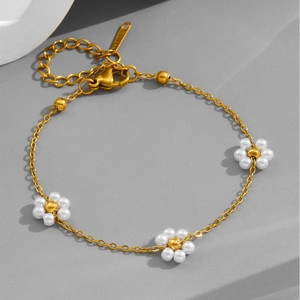 Elegant gold flower and pearl stainless steel bracelet on a minimalist grey background