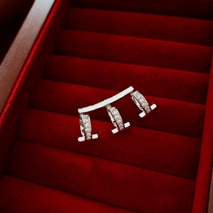 Detail of silver earring with three interlocking rings and sparkling crystals on red velvet