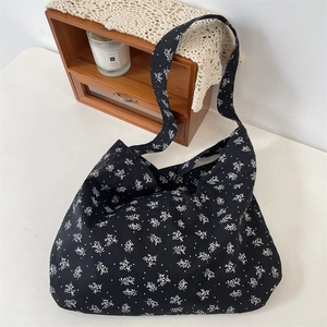 Détail d'un grand sac cabas en toile fleurie posé sur une table décorée de bougies