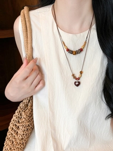 Detail of wooden beads and double-layered necklace with heart saturn charm pendant