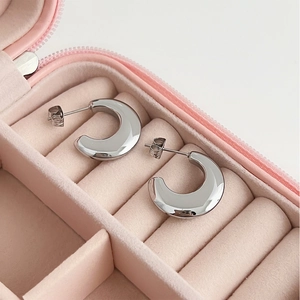 Elegant silver C-shaped stainless steel stud earrings displayed in a pink velvet jewelry box