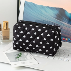 Close-up of black quilted cotton makeup bag with white hearts on a laptop keyboard