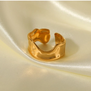 Detailed view of the golden irregular wavy texture on a minimalist adjustable open ring